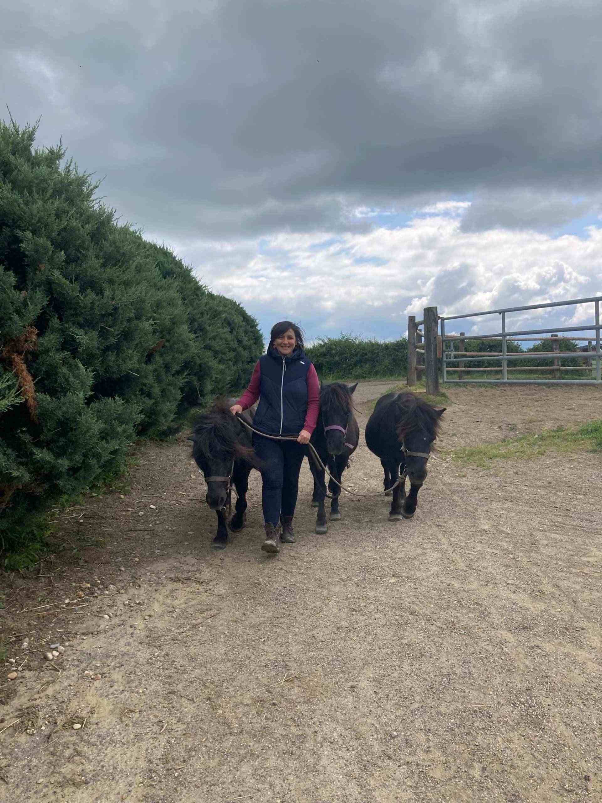 Femme marchant avec deux poneys